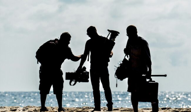 Sylwetki ekipy filmowej z kamerą na plaży o zmierzchu